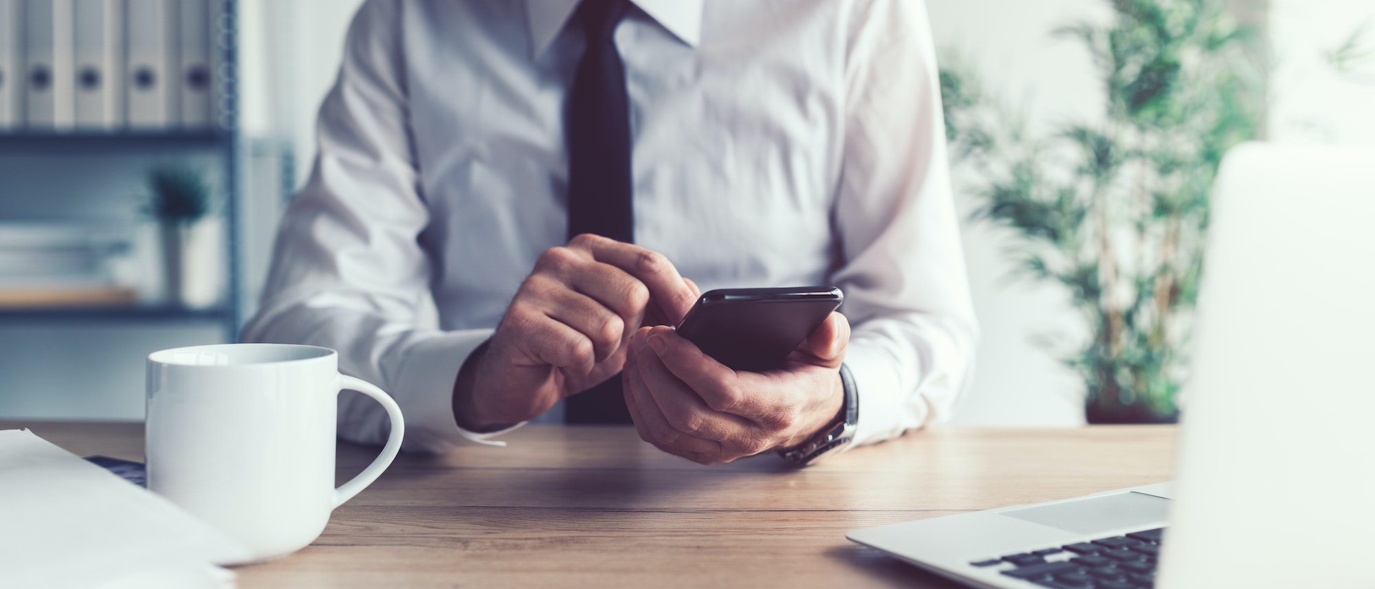 Business communication concept, businessman using mobile smart phone in office to send text message